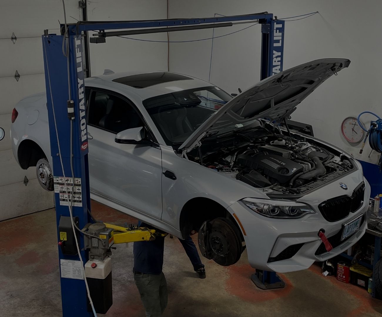 BMW vehicle on a rotary lift with hood open, showcasing engine for servicing, reflecting Schneller BMW's commitment to quality maintenance and performance tuning.